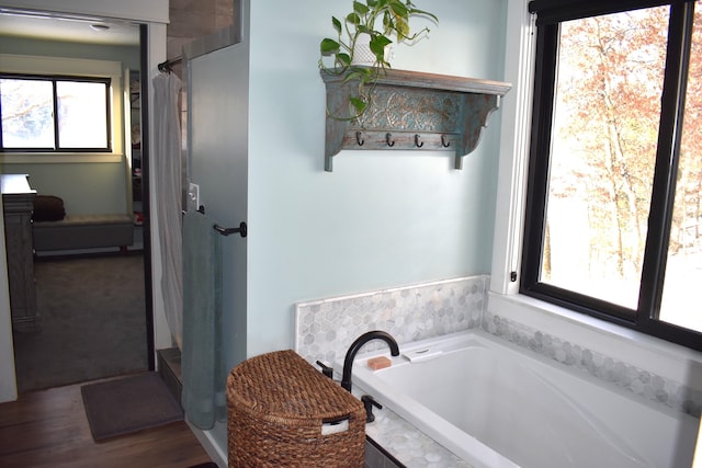 bathroom with independent shower and bath and hardwood / wood-style floors