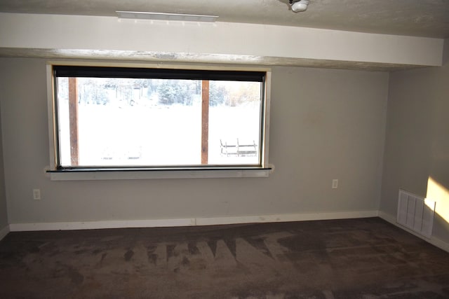 unfurnished room featuring dark colored carpet and plenty of natural light