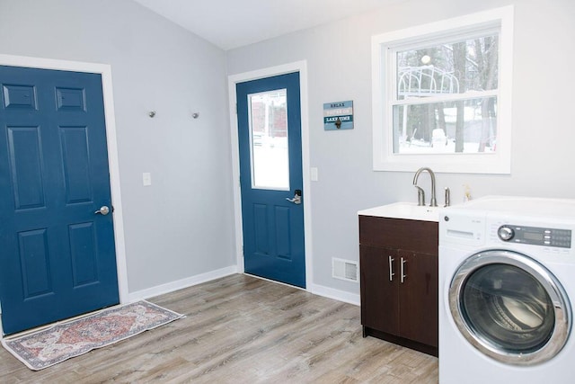 washroom with cabinets, light hardwood / wood-style floors, washer / clothes dryer, and sink