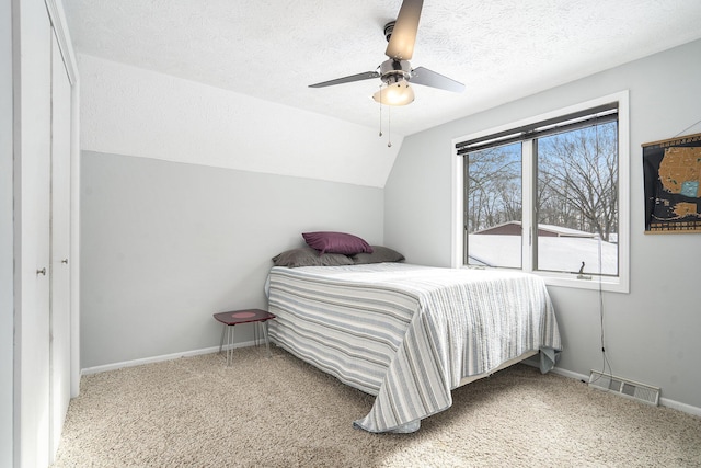 carpeted bedroom with ceiling fan, a textured ceiling, a closet, and lofted ceiling