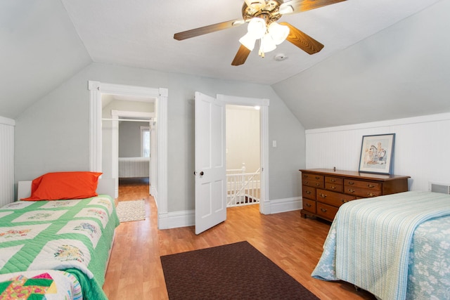 bedroom with ceiling fan, vaulted ceiling, and light wood-type flooring