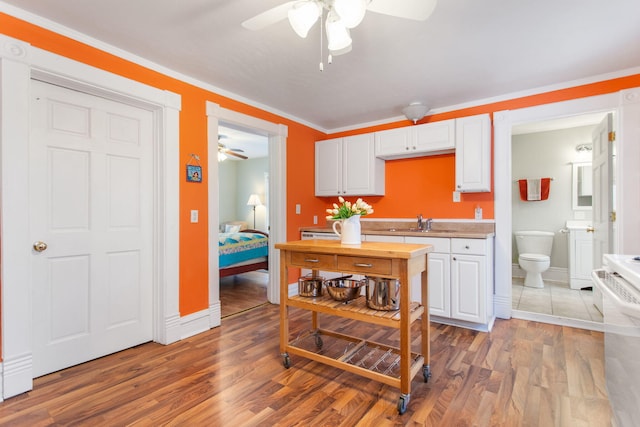 kitchen featuring hardwood / wood-style floors, sink, ornamental molding, white cabinetry, and washer / clothes dryer