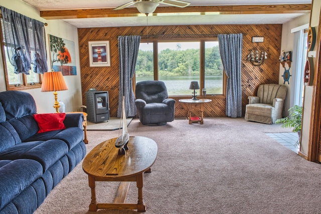 carpeted living room with beam ceiling, wooden walls, and ceiling fan