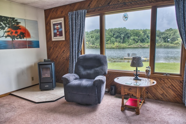 sitting room featuring carpet flooring, wood walls, and a water view