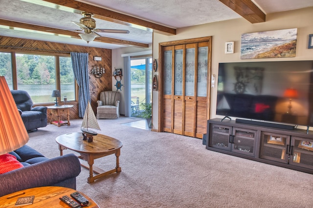 carpeted living room featuring beamed ceiling, a healthy amount of sunlight, a textured ceiling, and wooden walls