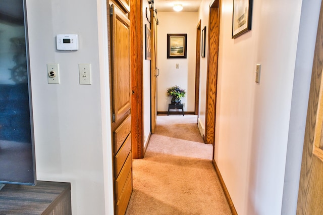 corridor with a barn door and light colored carpet