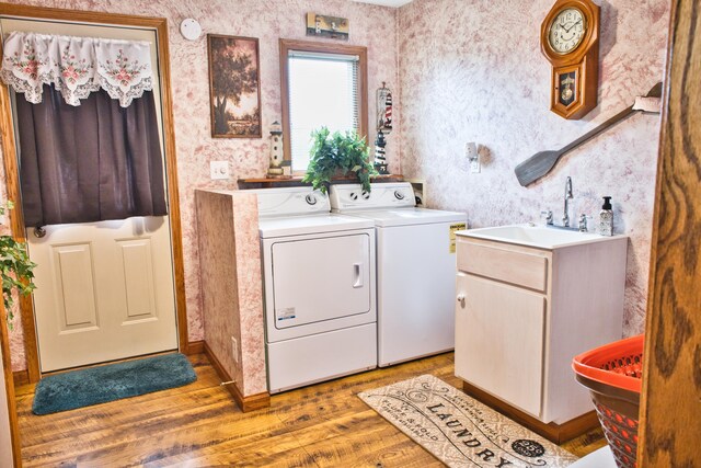 laundry area featuring hardwood / wood-style flooring, washing machine and dryer, and cabinets