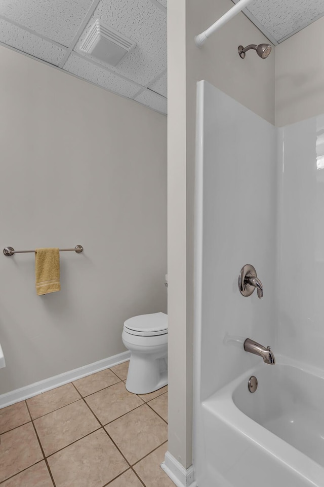 bathroom with toilet, shower / bath combination, a drop ceiling, and tile patterned floors