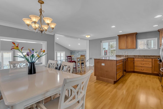 kitchen with a notable chandelier, light wood-type flooring, dishwasher, pendant lighting, and light stone counters