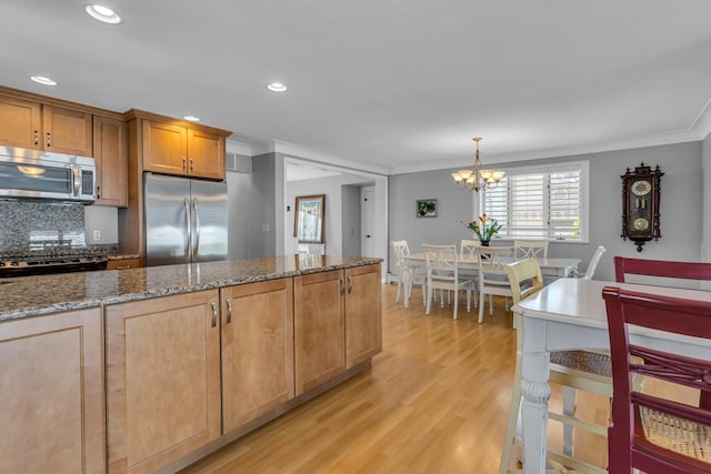 kitchen with decorative light fixtures, decorative backsplash, stainless steel appliances, ornamental molding, and dark stone counters