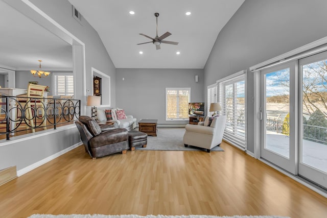 living room featuring vaulted ceiling, light hardwood / wood-style floors, and ceiling fan with notable chandelier