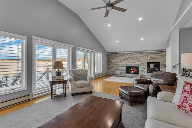 living room featuring light wood-type flooring, vaulted ceiling, plenty of natural light, and a stone fireplace