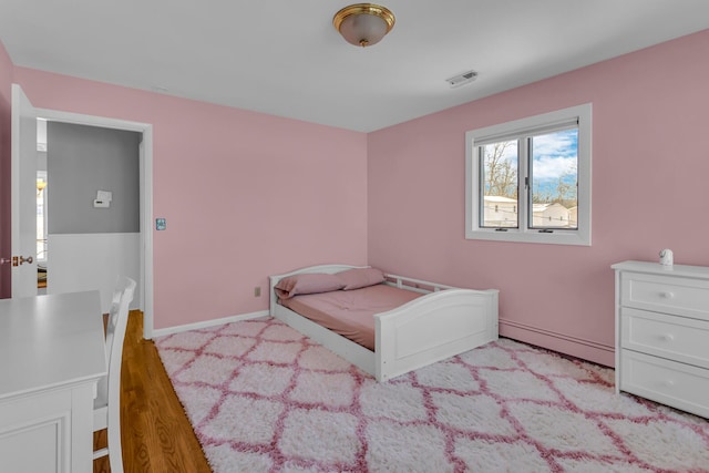 bedroom featuring a baseboard heating unit and light hardwood / wood-style flooring