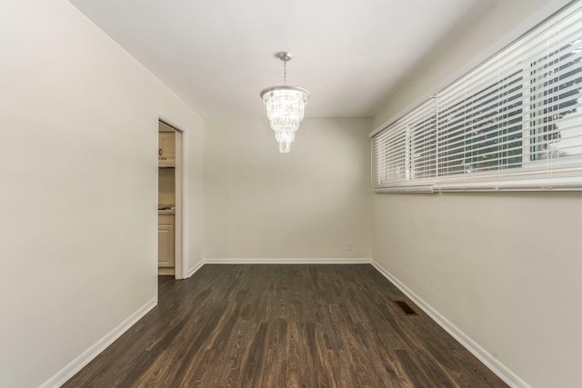 unfurnished dining area with visible vents, baseboards, an inviting chandelier, and dark wood-style floors