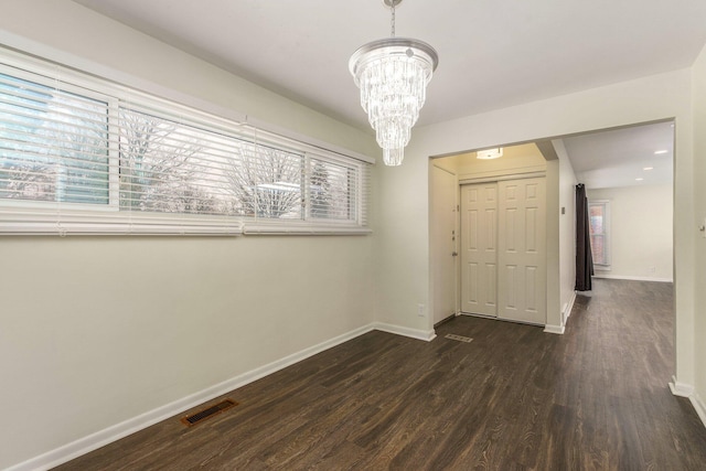 interior space featuring dark wood finished floors, visible vents, a chandelier, and baseboards