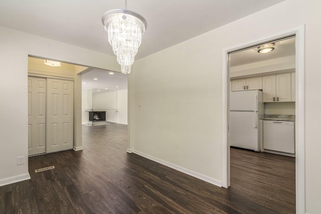 unfurnished dining area featuring visible vents, dark wood-style floors, baseboards, and a chandelier