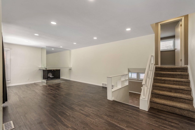 unfurnished living room featuring a multi sided fireplace, visible vents, recessed lighting, and wood finished floors