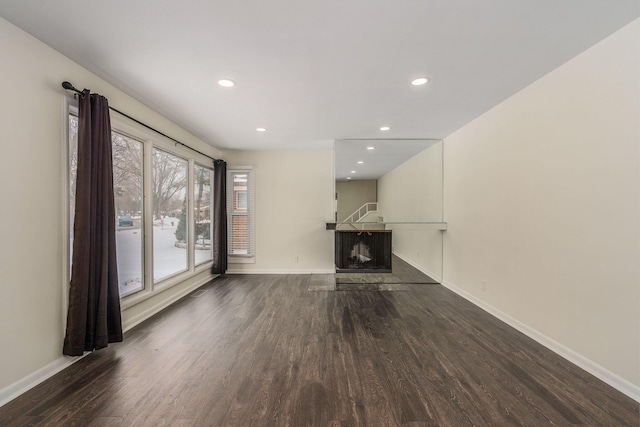 unfurnished living room featuring recessed lighting, baseboards, wood finished floors, and a fireplace