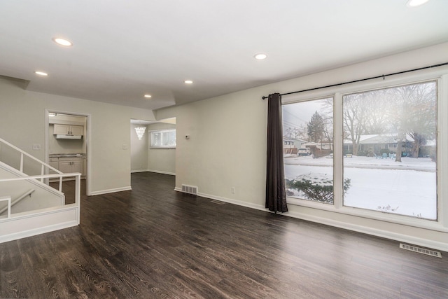 unfurnished living room with dark wood finished floors, recessed lighting, baseboards, and visible vents