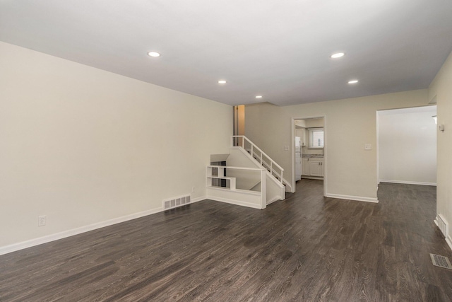 spare room with dark wood-type flooring, stairway, and visible vents