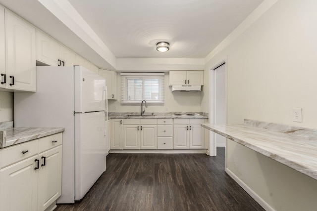 kitchen featuring dark wood-type flooring, under cabinet range hood, freestanding refrigerator, white cabinetry, and a sink