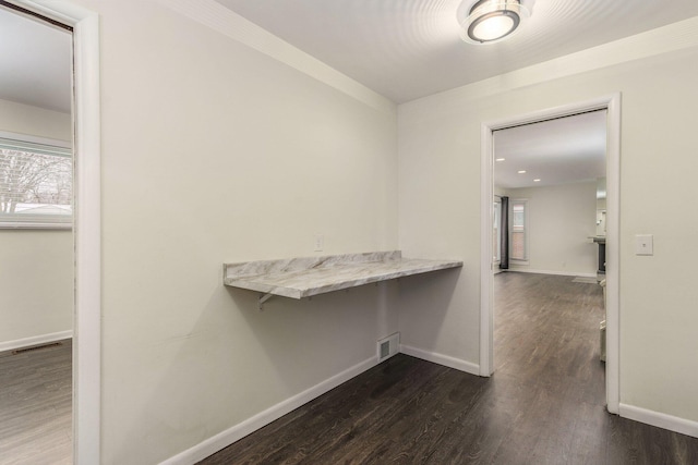 corridor with visible vents, baseboards, and dark wood finished floors