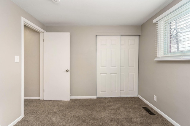 unfurnished bedroom with a closet, visible vents, baseboards, and carpet floors