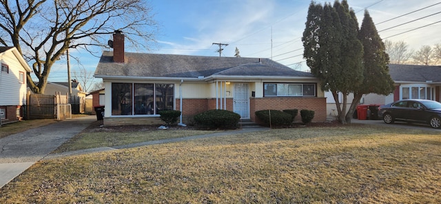 view of front of house featuring brick siding, a chimney, a front lawn, and fence