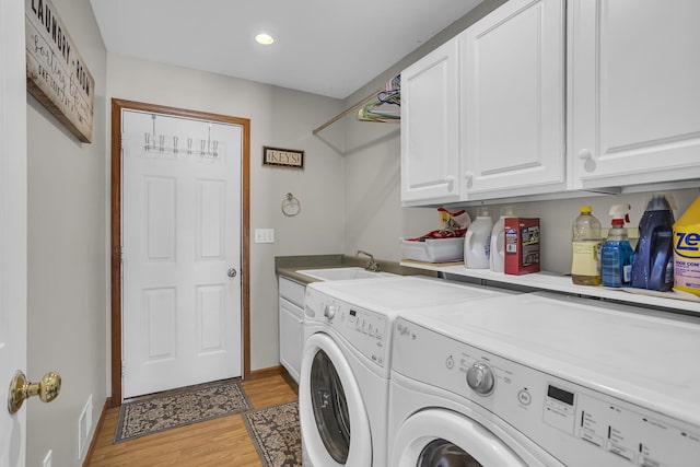 washroom featuring light wood-type flooring, independent washer and dryer, sink, and cabinets