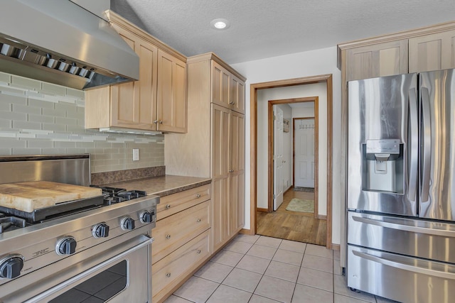 kitchen with light brown cabinets, stainless steel appliances, a textured ceiling, light tile patterned floors, and island range hood