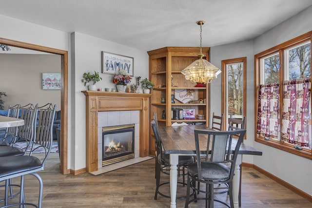 dining area featuring a fireplace, dark wood-type flooring, a chandelier, and a textured ceiling