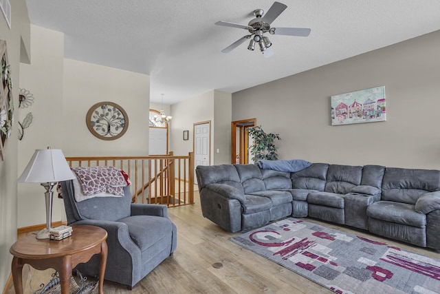 living room featuring light wood-type flooring, a textured ceiling, and ceiling fan with notable chandelier