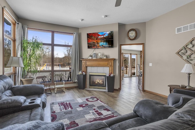 living room featuring a textured ceiling, light hardwood / wood-style flooring, and a fireplace