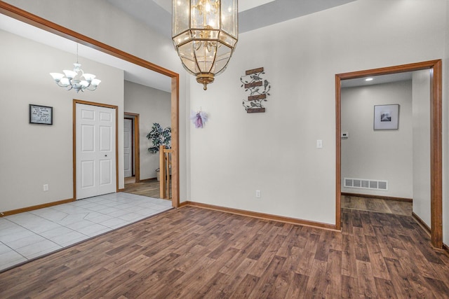 empty room featuring an inviting chandelier and wood-type flooring