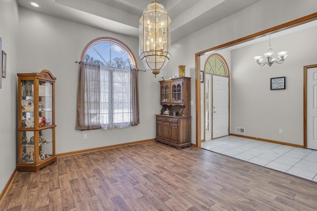 entrance foyer with light wood-type flooring, a chandelier, and a tray ceiling