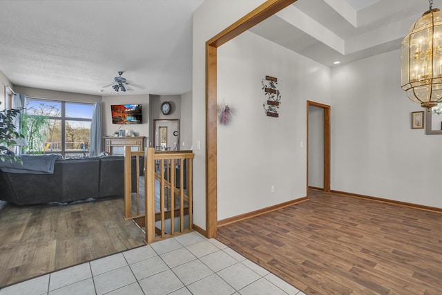 unfurnished living room featuring light tile patterned flooring and ceiling fan with notable chandelier