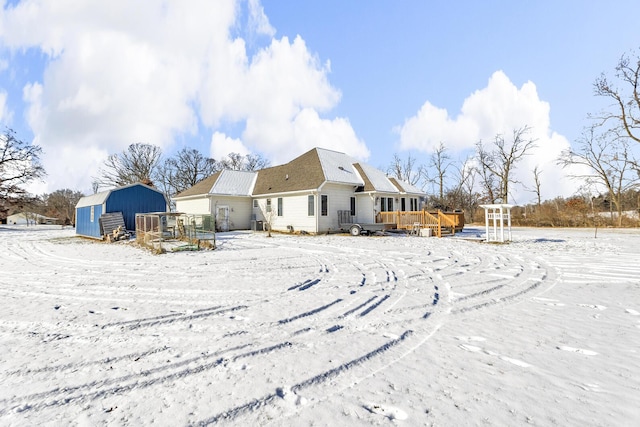 snow covered property featuring a deck and a storage unit