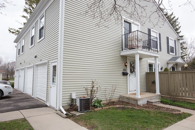 view of side of home with central AC unit, a garage, and a balcony