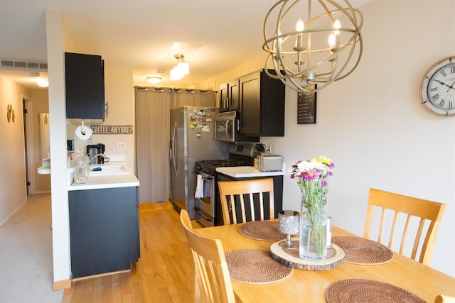 dining area with light hardwood / wood-style floors, an inviting chandelier, and sink