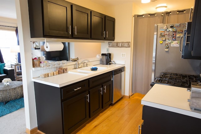 kitchen featuring dark brown cabinetry, sink, stainless steel appliances, and light hardwood / wood-style floors