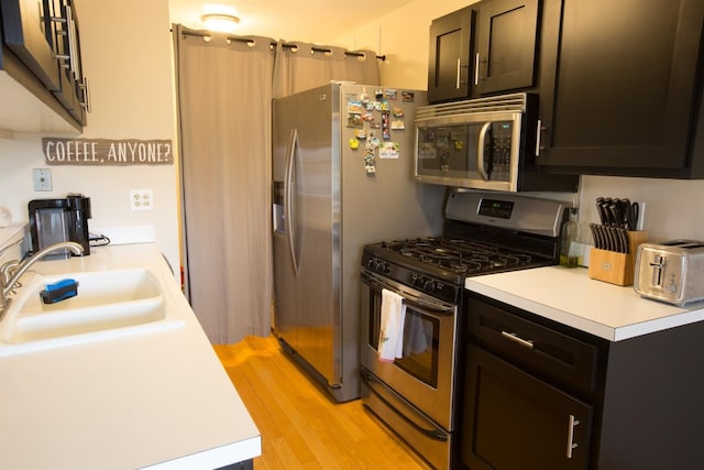 kitchen with sink, appliances with stainless steel finishes, and light hardwood / wood-style flooring