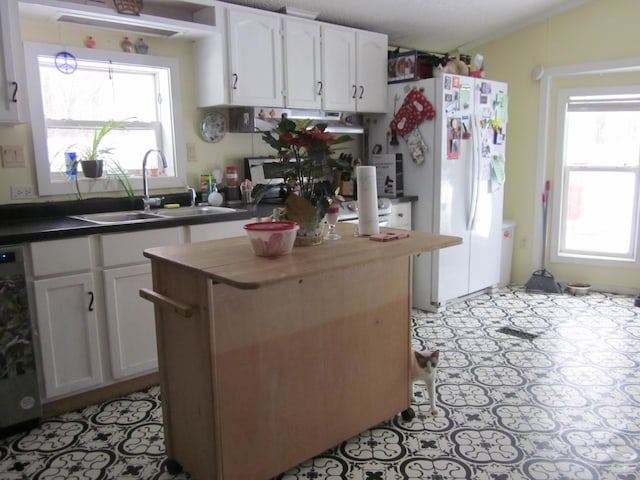 kitchen with sink, white refrigerator, white cabinetry, and dishwashing machine