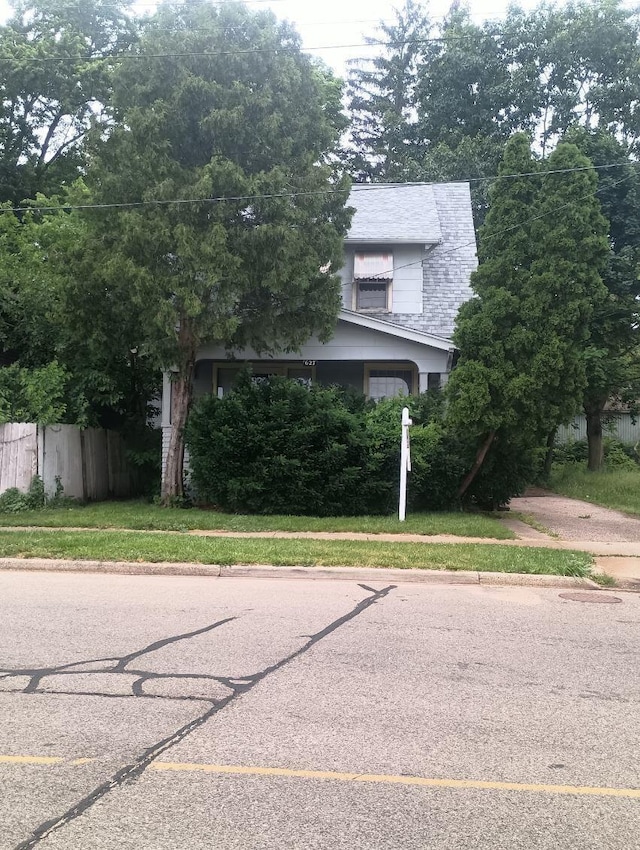 view of property hidden behind natural elements featuring a front yard