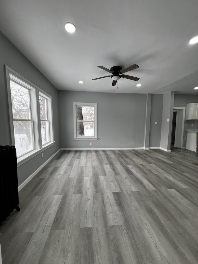 unfurnished living room featuring ceiling fan, radiator, and light hardwood / wood-style flooring