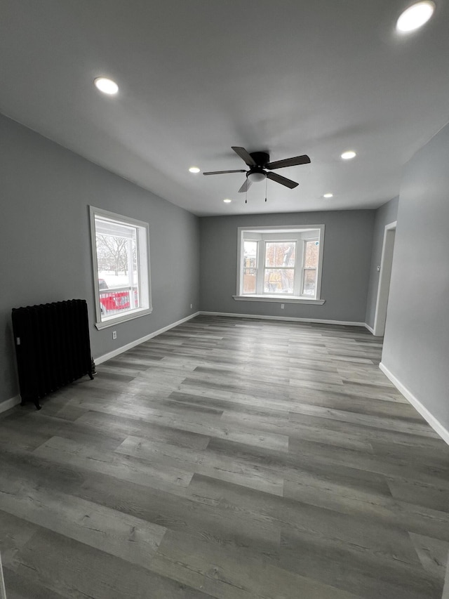 unfurnished room with hardwood / wood-style flooring, radiator, and ceiling fan