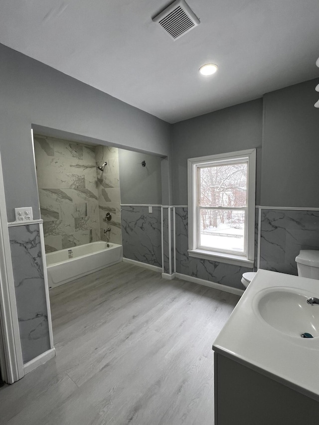 full bathroom with toilet, tiled shower / bath combo, hardwood / wood-style floors, and vanity