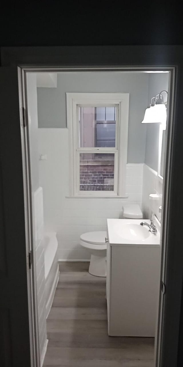 bathroom with vanity, wood-type flooring, tile walls, and a bathing tub