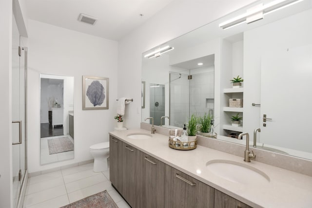 bathroom featuring toilet, vanity, tile patterned floors, and an enclosed shower