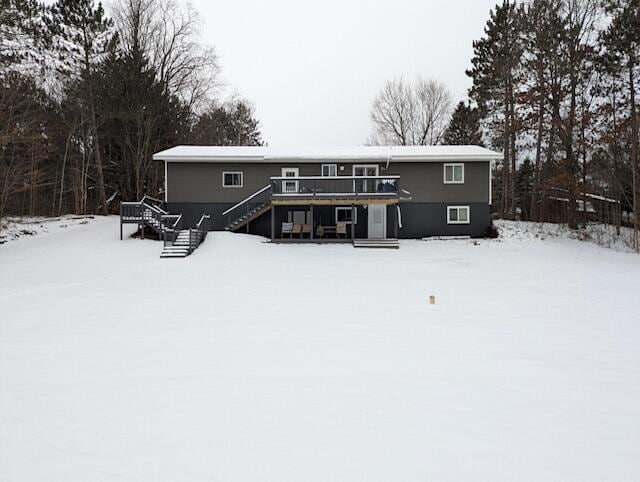 snow covered back of property with a deck