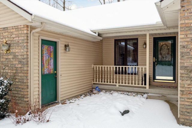 snow covered property entrance featuring a porch